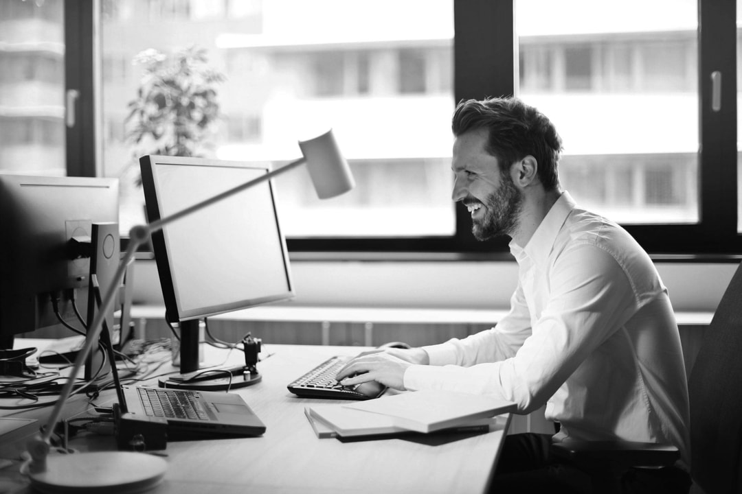 Men working at desk, smiling. Black and white picture.